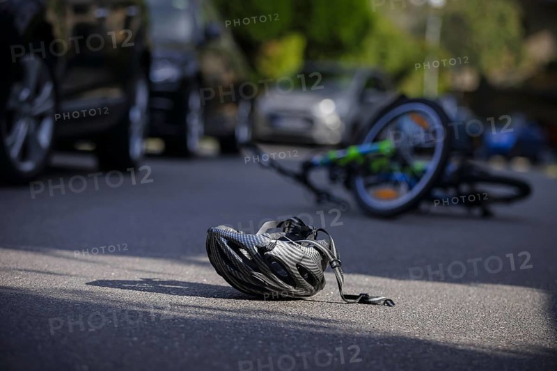 Symbol photo on the subject of bicycle accidents (posed scene) . A broken bicycle helmet lies next to a bicycle on a road Berlin, 21/08/2024