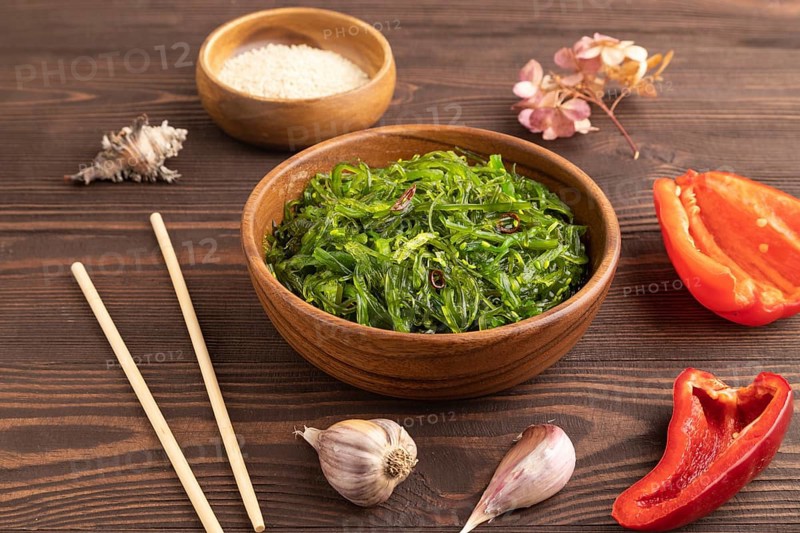 Chuka seaweed salad in wooden bowl on brown wooden background. Side view, close up