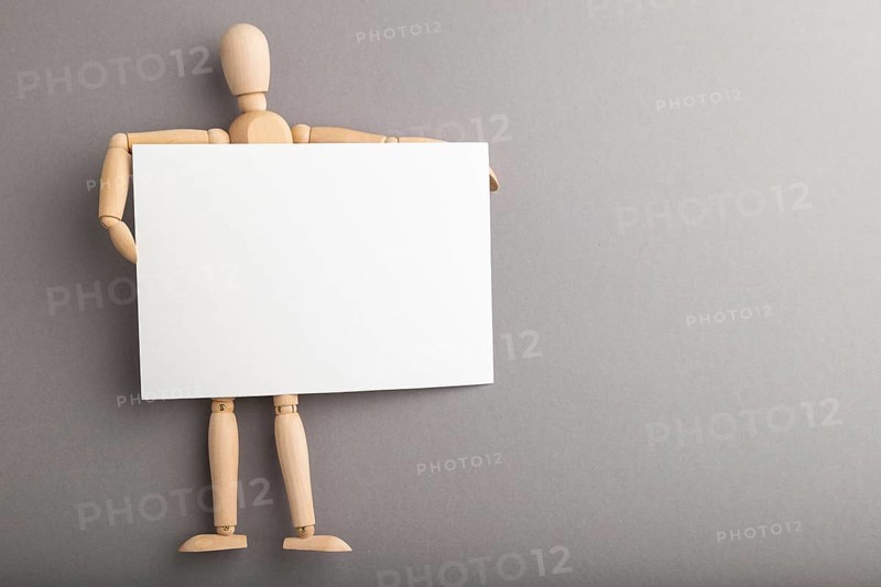 Wooden mannequin holding blank poster on gray pastel background. copy space, isolated, presentation concept