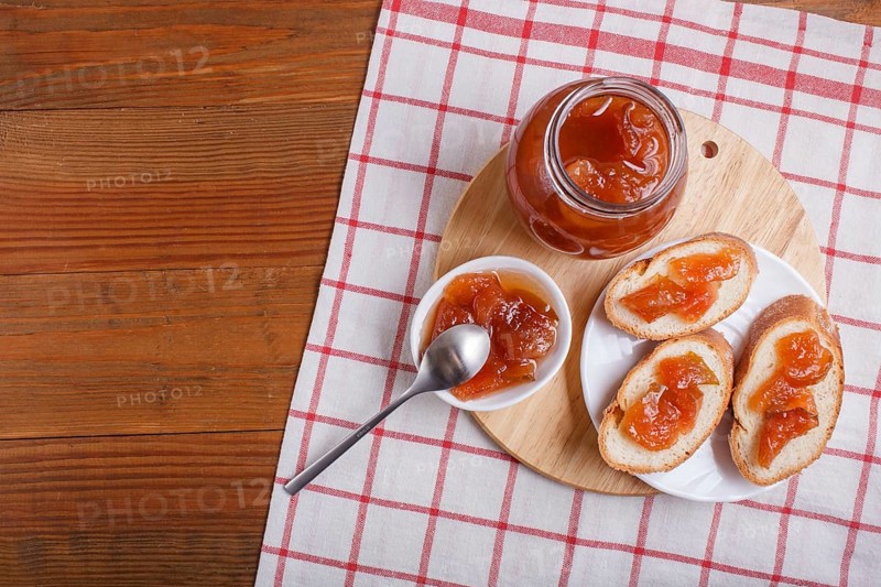 Pear jam in a glass jar on a linen tablecloth on a wooden table. Homemade, top view