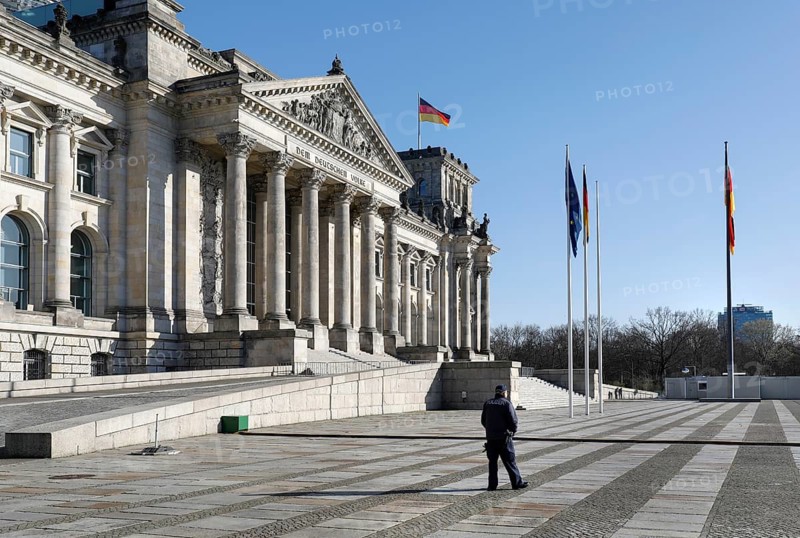 A policeman in front of the cordoned-off Reichstag in Berlin. Where many hundreds of people usually linger to visit the government district, there is now an eerie silence. Public life in Berlin has almost come to a standstill following the protective measures recently adopted to prevent the spread of the coronavirus. All sights, museums, squares, streets, restaurants, universities, 23.03.2020 are affected