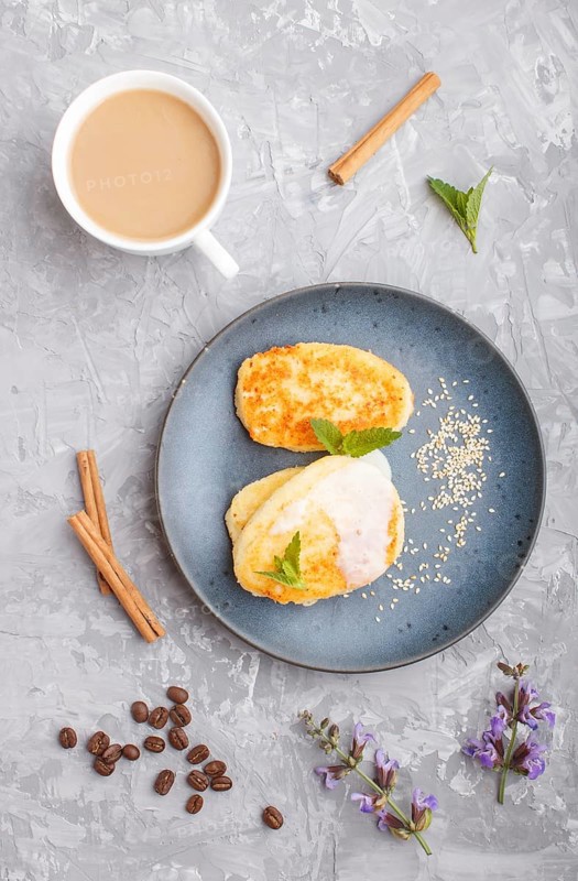 Cheese pancakes on a blue ceramic plate and a cup of coffee on a gray concrete background. top view, flat lay