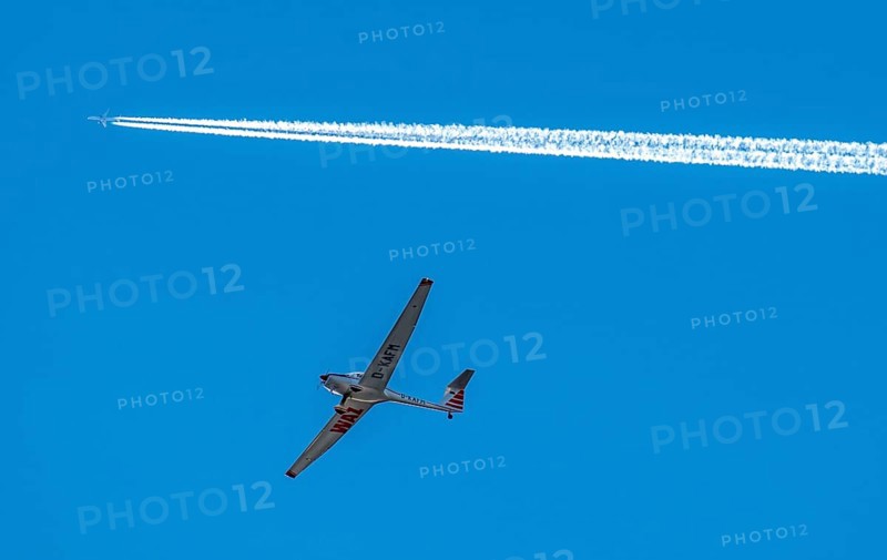 Twin-engine jet, passenger aircraft, with contrails, in the sky, below a motorised sailplane