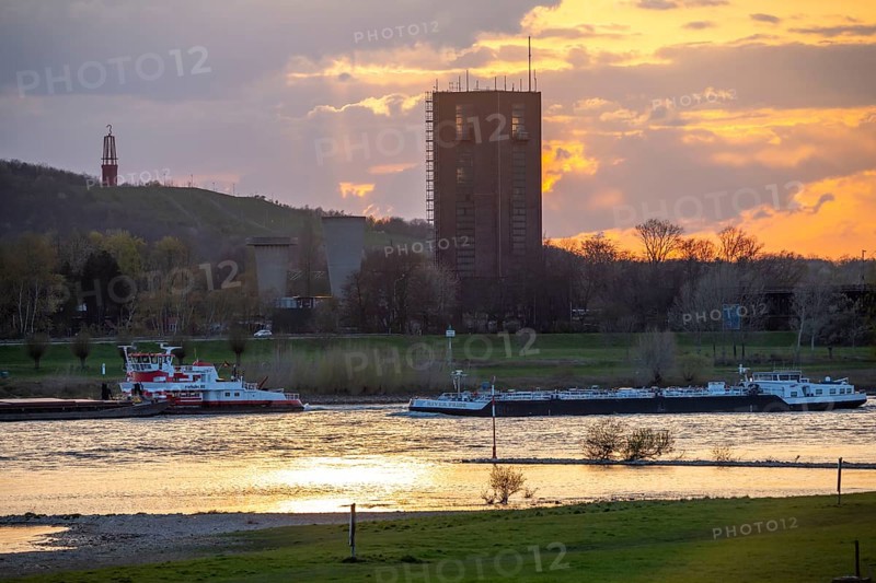 Cargo ship on the Rhine near Duisburg-Beeckerwerth, Rheinpreussen spoil tip in Mörs, spoil tip sign Das Geleucht, winding tower of the former Rheinpreußen Schacht VIII colliery, Duisburg, North Rhine-Westphalia, Germany, Europe