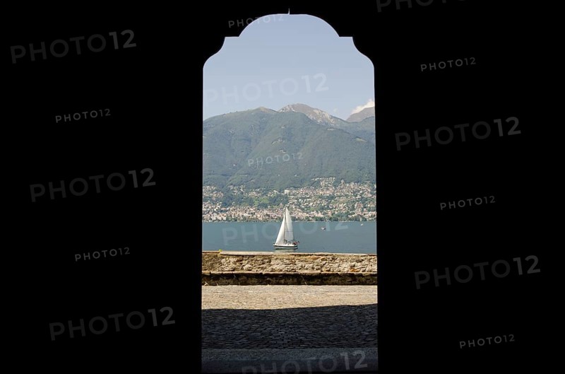 Looking at a Sailing Boat Through an Open Door on Lake Maggiore with Mountain in a Sunny Summer Day in Ticino, Switzerland, Europe