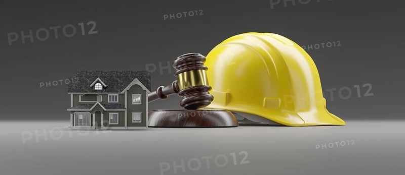 Miniature model house, yellow hard hat and gavel on a gradated background