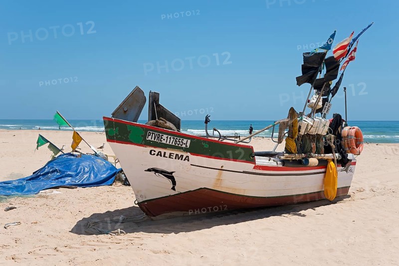 Traditional fishing boat with colourful flags on the beach, looking into the distant blue coloured sea, Fishing boats on the beach, Monte Gordo, Faro, Algarve, Portugal, Europe