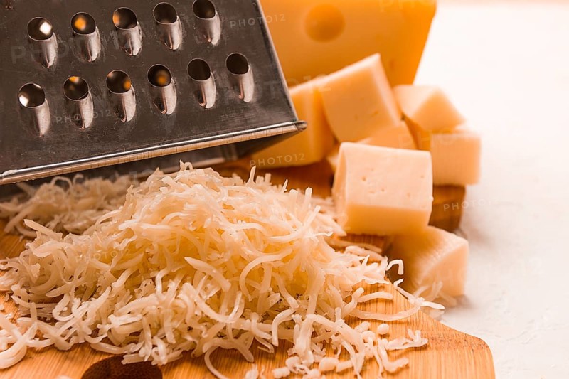 Grated cheese, Maasdam, on a cutting board, grater and cheese knife, close-up, no people
