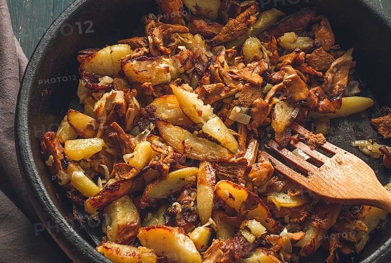 Fried chanterelles with mushrooms, in a clay pan, close-up, top view, selective focus