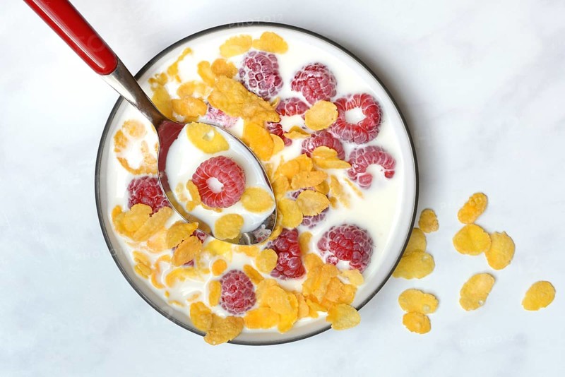 Raspberries and cornflakes with milk in a bowl, Rubus idaeus
