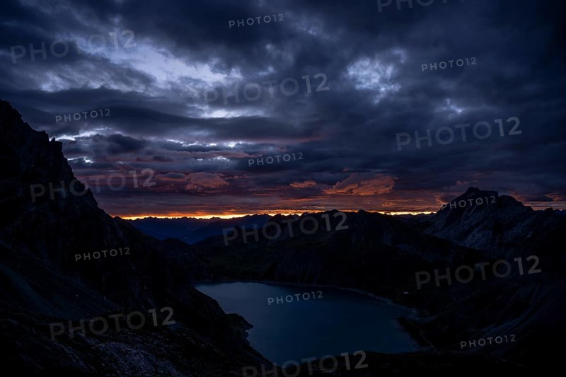 Lake Lüner See with Montafon mountains and dramatic cloudy sky at sunrise, Tschagguns, Rätikon, Montafon, Vorarlberg, Austria, Europe