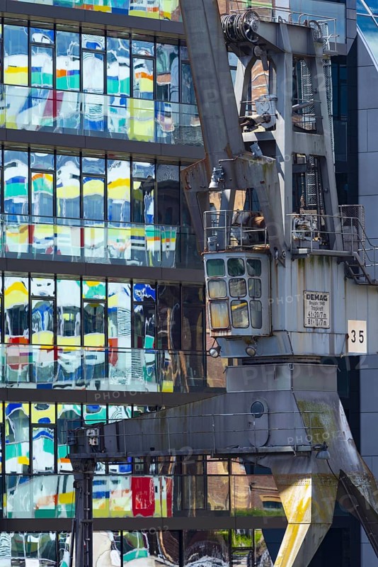 Old crane in front of the glass façade of an office building, reflecting the Colorium high-rise, façade with coloured glass panels, architect William Alsop, Julo-Levin-Ufers in Medienhafen, Düsseldorf, North Rhine-Westphalia, Germany, Europe
