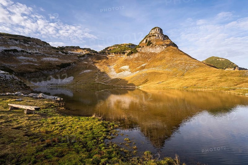 Lake Augstsee and the Atterkogel mountain on the Loser. A bench on the left. Autumn, good weather, blue sky. Golden hour. Reflection. Altaussee, Bad Aussee, Ausseer Land, Totes Gebirge, Styria, Upper Austria, Austria, Europe