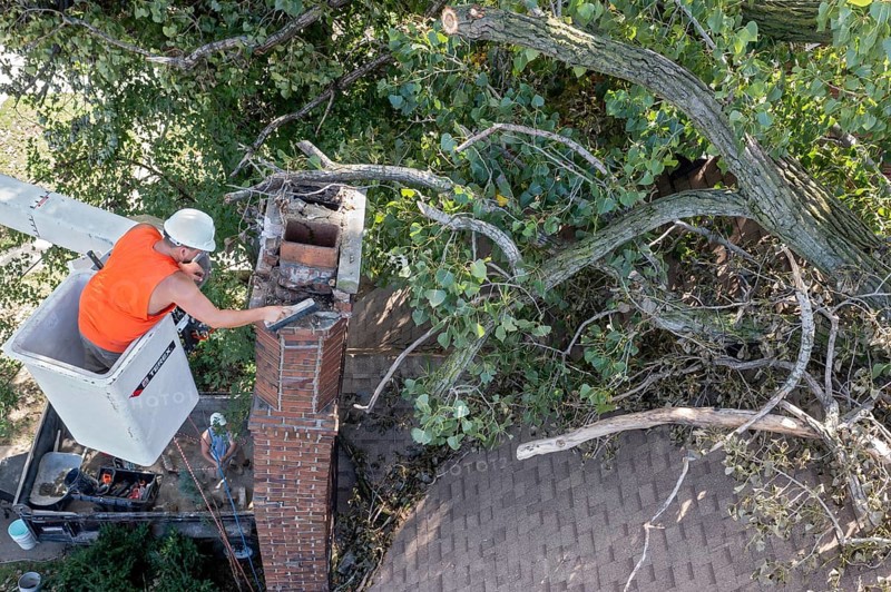 Detroit, Michigan, A worker dismantles a brick chimney after a storm with 70mph wind gusts blew down a 15-ton, 110-foot cottonwood. The tree cracked the chimney, leaving it leaning and threatening to crash through the home's roof
