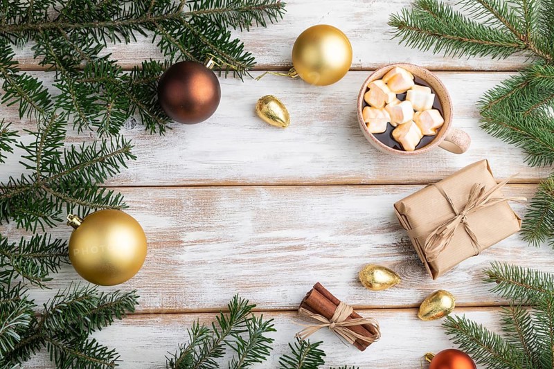 Christmas or New Year frame composition. Decorations, box, golden balls, cinnamon, fir and spruce branches, cup of coffee, on a white wooden background. Top view, copy space, flat lay