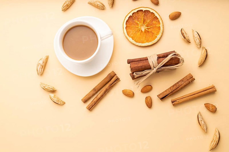 Composition with almonds, cinnamon and cup of coffee on orange pastel background. Blank, flat lay, top view, still life, copy space