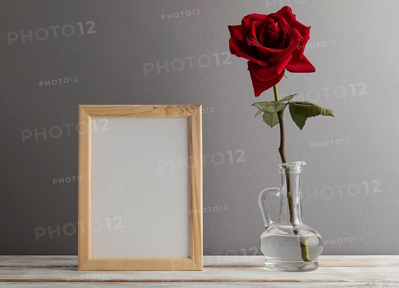 White wooden frame mockup with red rose in glass on gray paper background. Blank, vertical orientation, still life, copy space