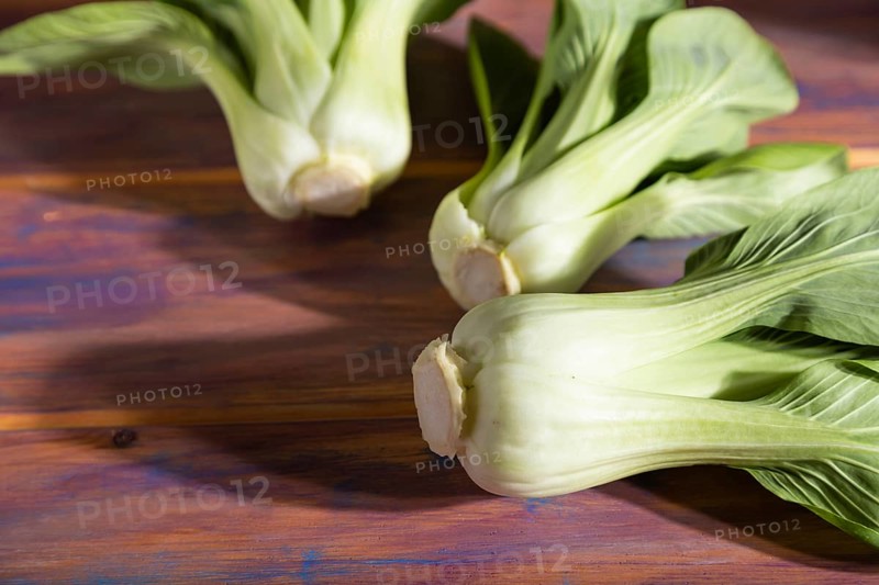 Fresh green bok choy or pac choi chinese cabbage on a colored wooden background. Hard light, contrast. Side view, close up, selective focus