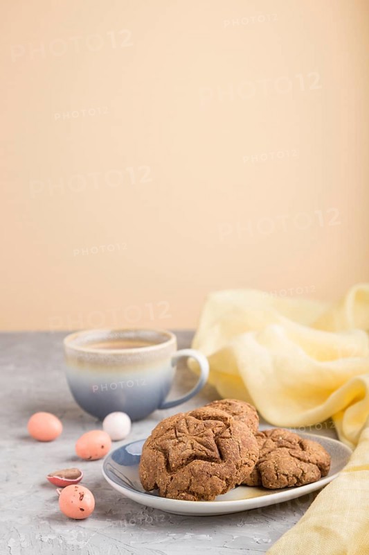 Homemade oatmeal cookies with a cup of cocoa and a yellow textile on a gray and orange background. side view, close up, selective focus