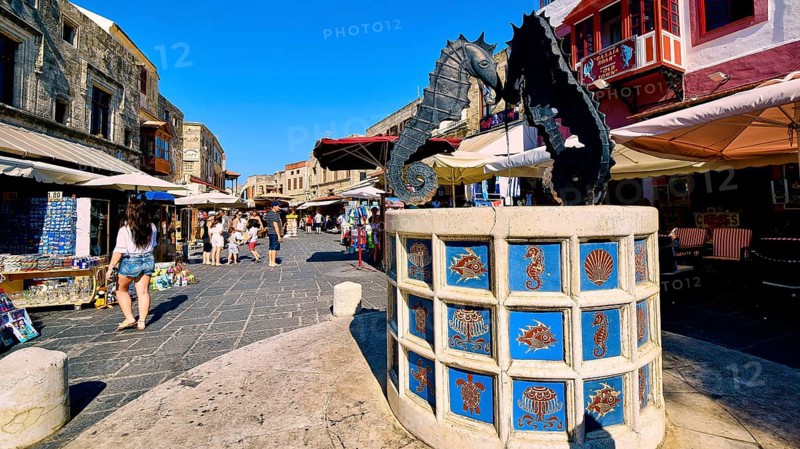 Martyrs Square, Lively market square with a fountain showing seahorse statues, surrounded by shops and historic buildings, Rhodes Old Town, Rhodes Town, Rhodes, Dodecanese, Greek Islands, Greece, Europe