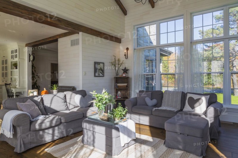 Dark grey upholstered ektorp model sofas in living room with rug and stained oak wood floorboards inside country style home, Quebec, Canada, North America