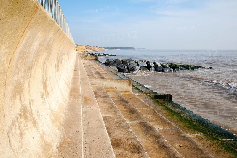 Curved wave return sea wall, steps and rock armour groynes, forming coastal defences at Southwold, Suffolk, England, United Kingdom, Europe