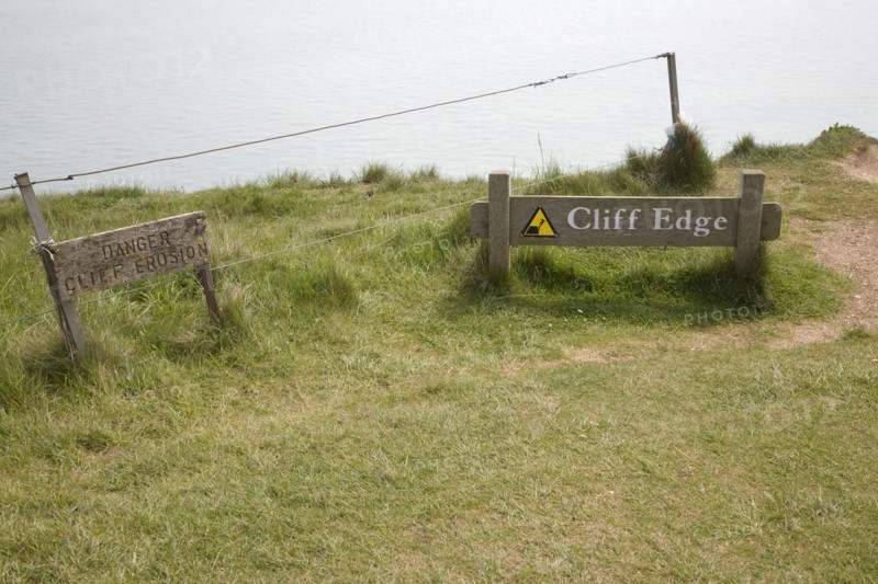 Wooden signs warning of the danger of cliff erosion at the top of the sheer cliffs at Beachy Head, East Sussex, England, United Kingdom, Europe