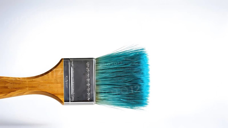 Thick paintbrush dipped in cyan bristles dripping onto a white background, AI generated