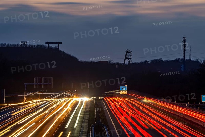 Evening traffic on the A2 motorway at the Recklinghausen junction heading west, in the background the headframes of the former Ewald colliery, North Rhine-Westphalia, Germany, Europe