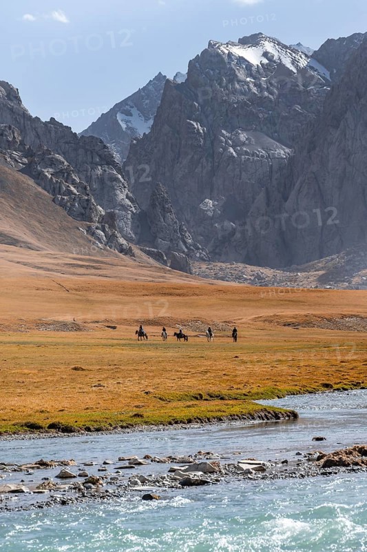 Rider in mountain landscape with yellow meadows, river Kol Suu and mountain peaks with glacier, Keltan Mountains, Sary Beles Mountains, Tien Shan, Naryn Province, Kyrgyzstan, Asia