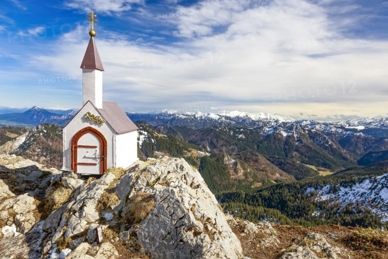 Whitewashed miniature chapel on the Hochgern summit in the Chiemgau Alps under partly cloudy skies in Bavaria Germany Europe