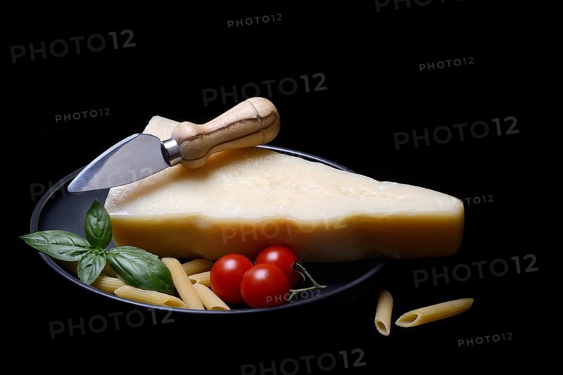 A piece of Parmesan cheese with cheese knife, pasta and tomatoes, Italy, Europe