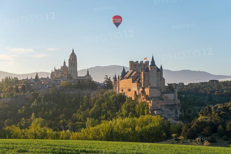 Impressive view of a historic castle with a hot air balloon in the sky and green fields in the foreground at sunrise, Cathedral, Alcázar, Alcazar, Segovia, Castilla y León, Leon, Spain, Europe