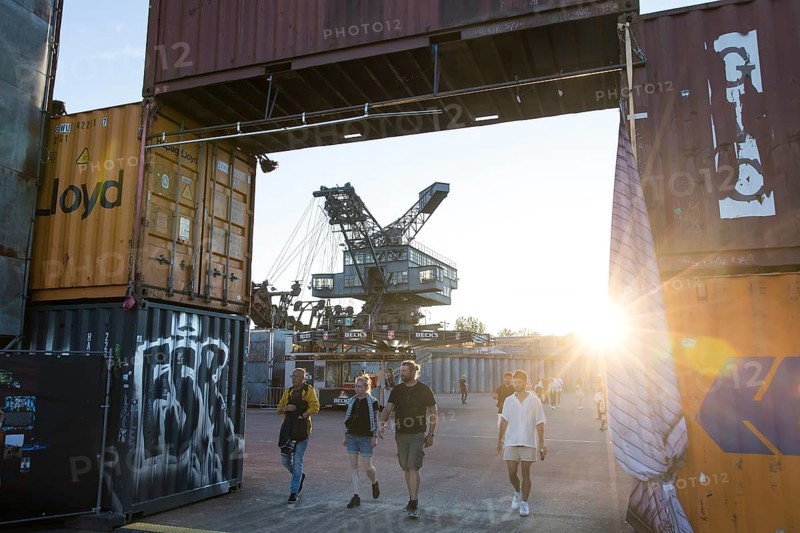 Festival visitors walk in the evening sun through a bridge made of containers in front of one of the excavators at the Melt Festival in Ferropolis on 13 July 2024. After a total of 27 years, the festival will take place for the last time in 2024