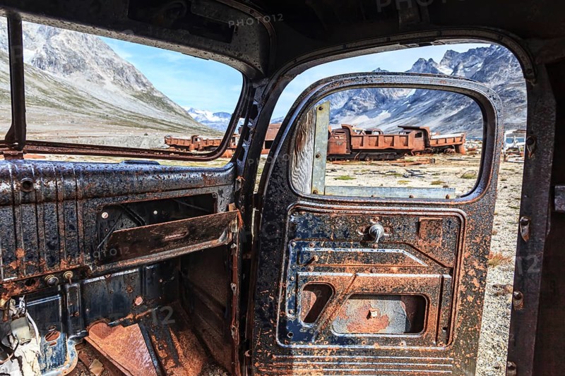 Interior view of a rusty car in front of steep mountains, remains of a US airbase from the Second World War, Ikateq Fjord, East Greenland, Greenland, North America