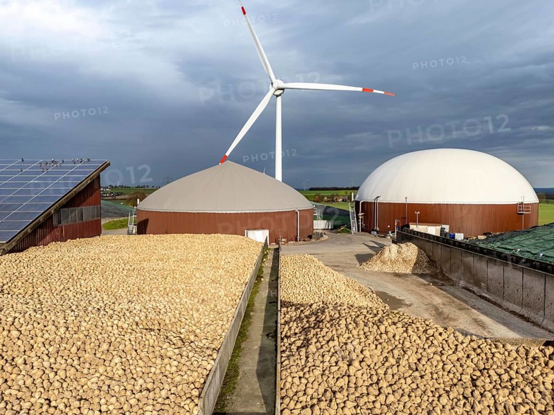 Biogas plant produces gas from various biomass, here the sugar beet store, the electricity is produced in combined heat and power plants with the biogas produced and sold to companies in the neighbouring industrial estate, the heat generated is fed into a local heating network, gas storage technical building with solar roofs and wind power plant, Ense, North Rhine-Westphalia, Germany, Europe