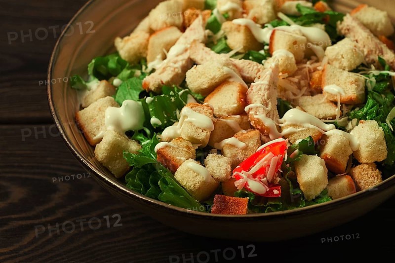 Fresh traditional Caesar salad, with chicken, on a wooden background, Top view, toned, horizontal no people