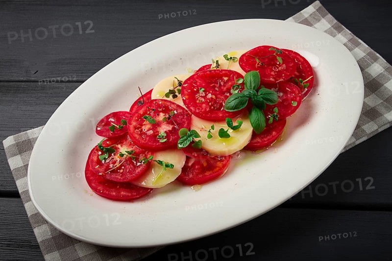 Caprese salad, Italian traditional dish, tomatoes with mozzarella cheese, basil and spices, top view, no people