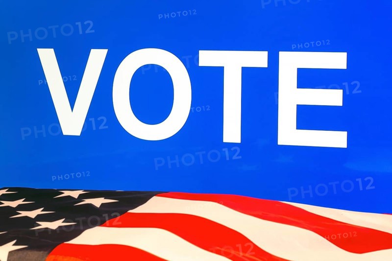 USA flag in front of a blue screen with the inscription VOTE