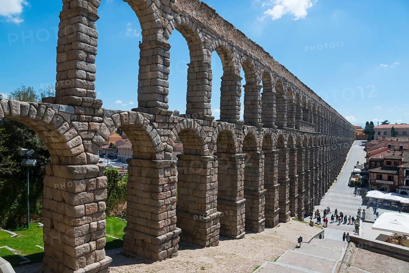 Historic aqueduct with stone arches, under a sunny sky with buildings in the background, Aqueduct, Segovia, Castilla y León, Leon, Spain, Europe
