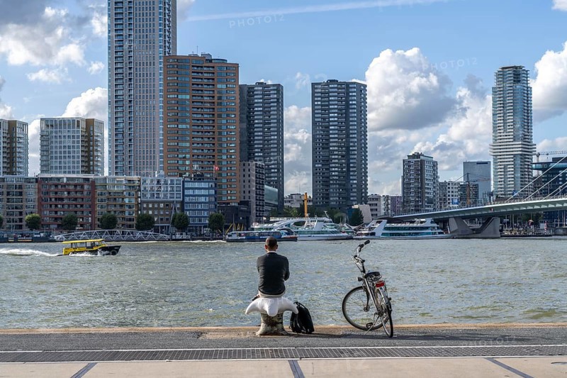 Skyline at the Nieuwe Maas, skyscrapers, man taking a break at the riverbank, Rotterdam, Netherlands