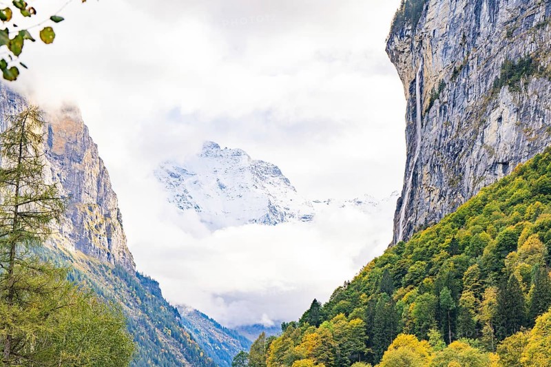 Snow-capped mountains rise in a tree-lined valley, clouds pass by, Lauterbrunnen, Switzerland, Europe