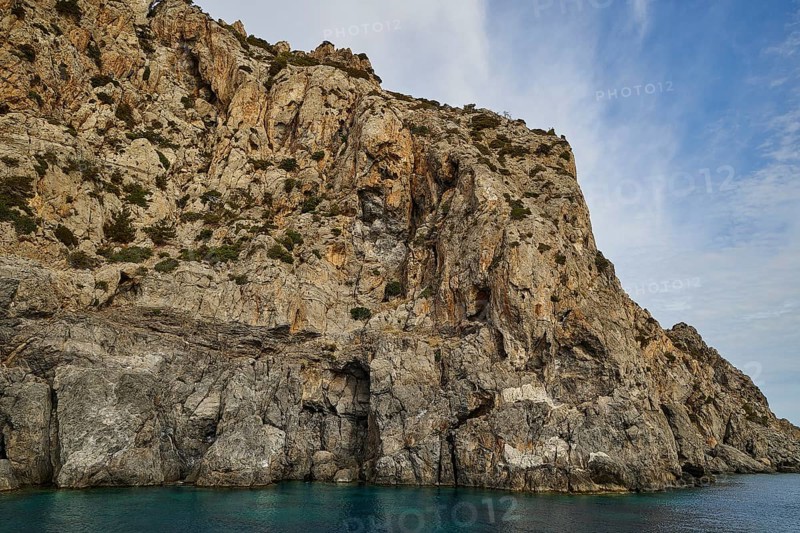 Steep cliff on the shore, light blue sky with few clouds above, boat tour Saria, Saria Island, Karpathos, Dodecanese, Greek Islands, Greece, Europe