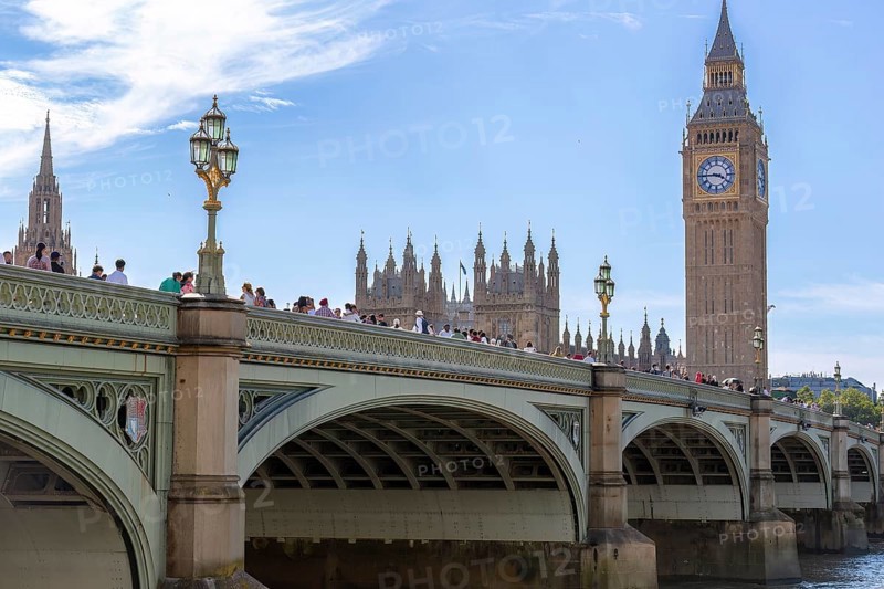 Tourists on a bridge in front of the famous landmark Big Ben under a blue sky, London, United Kingdom Great Britain