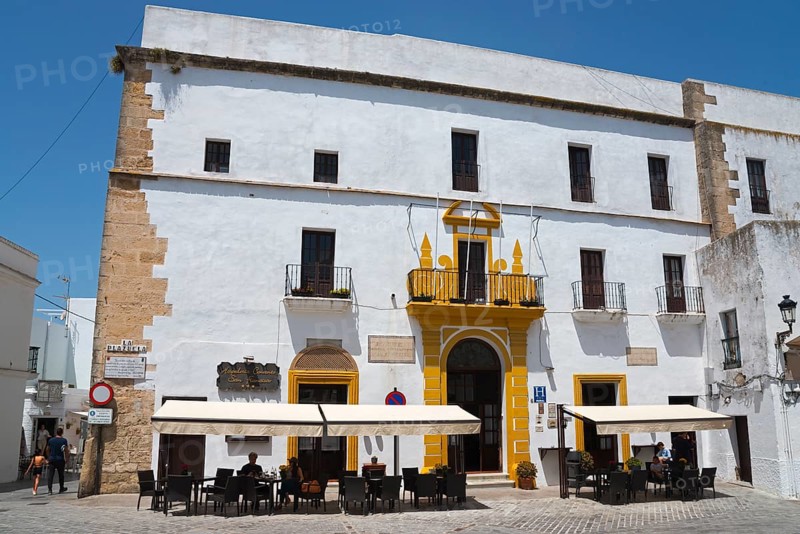 A historic building with a white façade and yellow entrance, including a street café with parasols, Convento de San Francisco, Hotel, Old Town, Vejer de la Frontera, Province of Cadiz, Cadiz, Andalusia, Spain, Europe