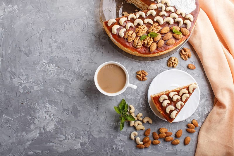 Homemade cake with caramel cream and nuts with cup of coffee on a gray concrete background. top view. flat lay, copy space