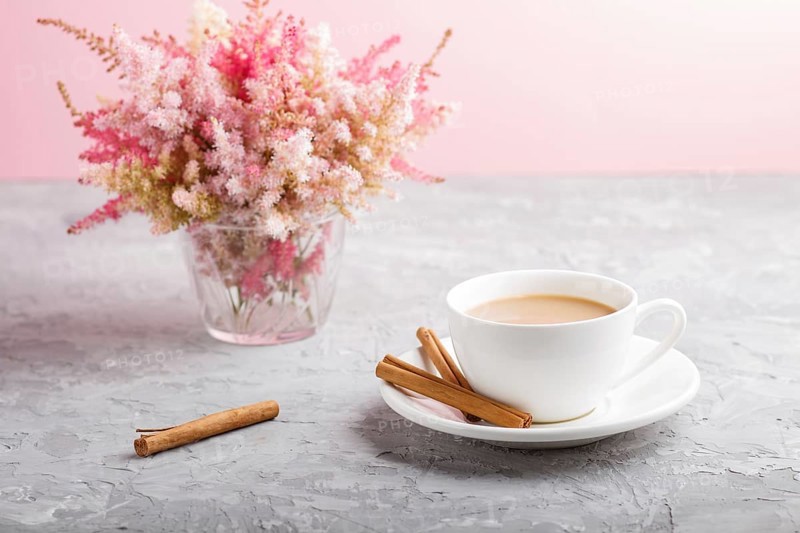 Pink and red astilbe flowers in glass and a cup of coffee on a gray and pink background. Morninig, spring, fashion composition. side view, close up, selective focus