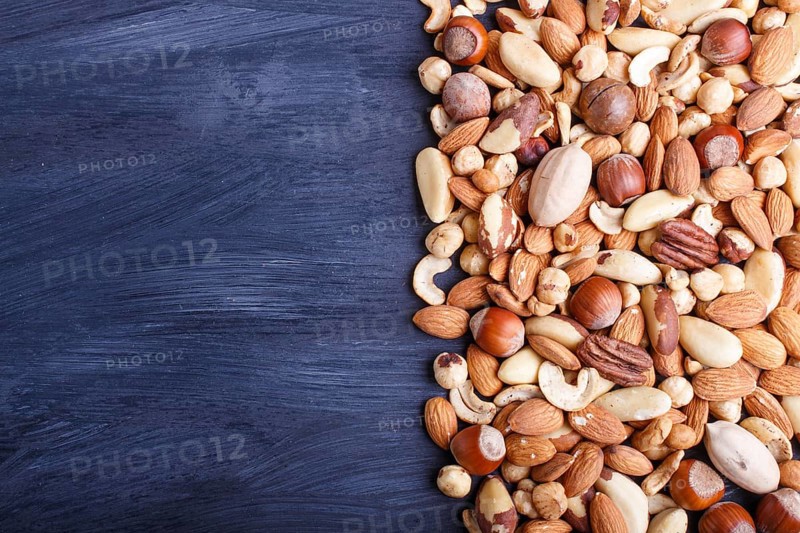 Mixed different kinds of nuts on black wooden background. hazelnut, brazil nut, almond, pumpkin seeds, cashew. with copy space, top view