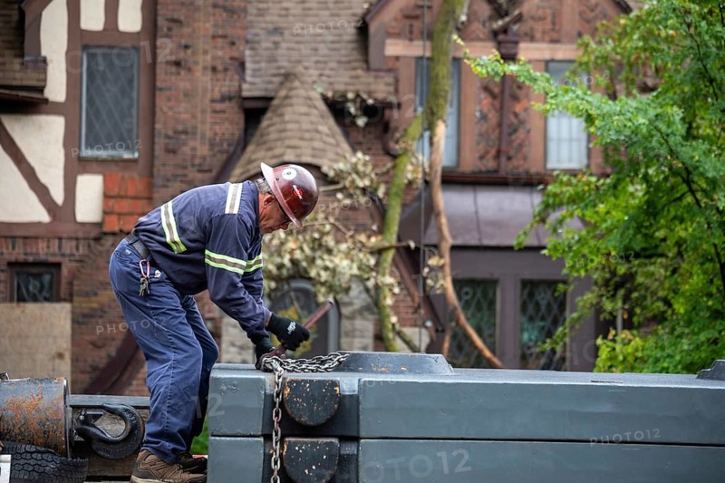 Detroit, Michigan, A storm with 70mph wind gusts blew down a 15-ton, 110-foot cottonwood, damaging three homes in the Morningside neighborhood. A dozen workers used two cranes, bucket trucks, and other equipment to remove the tree. A worker unfastens counterweights that will be placed on a 240 ton crane