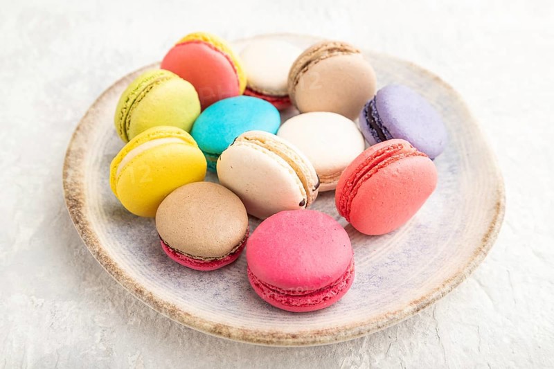 Multicolored macaroons on ceramic plate on gray concrete background. side view, still life, close up. Breakfast, morning, concept